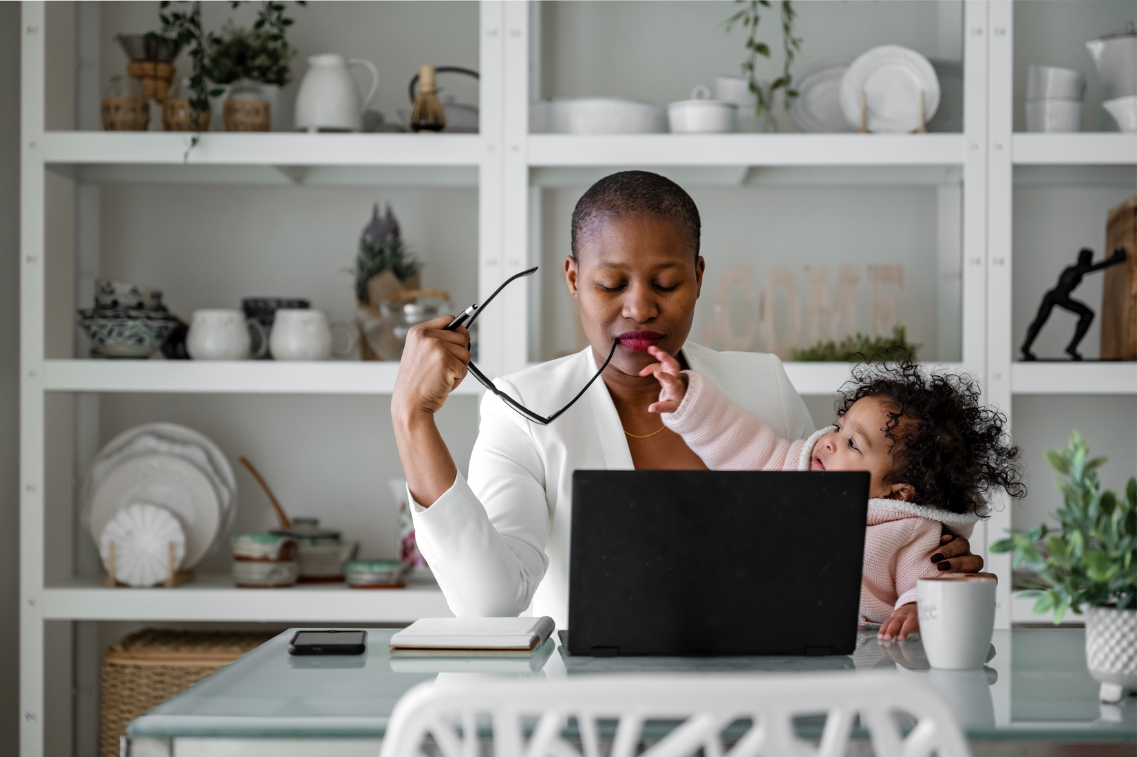 Woman Working on Laptop While Taking Care of Her Daughter